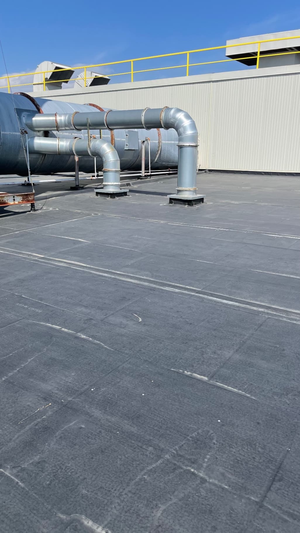 Completed EPDM flat roof with industrial ductwork and parapet rail on commercial building