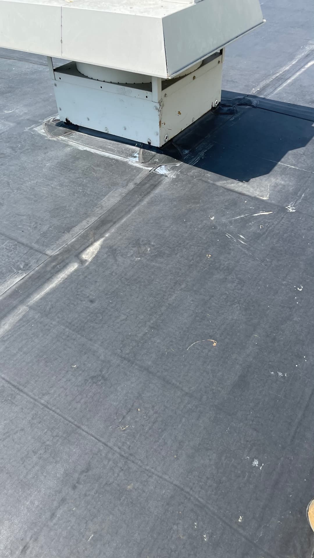 Close-up detail of EPDM roofing flashed around rooftop exhaust curb on commercial flat roof
