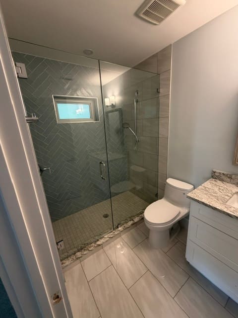 Guest bathroom with herringbone tile shower and frameless glass