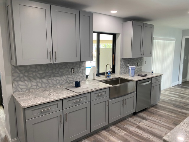 Gray shaker kitchen with farmhouse sink and patterned tile backsplash