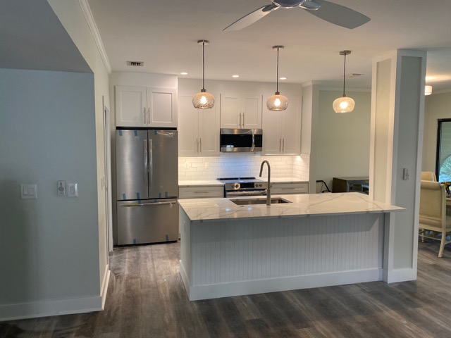 White kitchen remodel with waterfall quartz island and globe pendant lighting