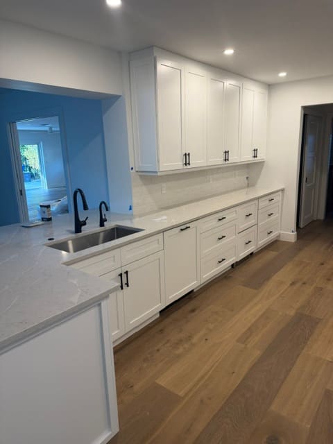 Bright white kitchen with extended quartz countertop and oak flooring