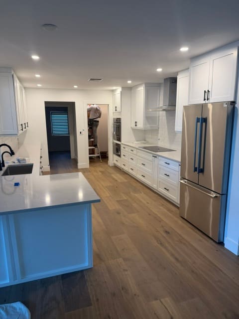 Modern white kitchen with French door refrigerator and oak floors