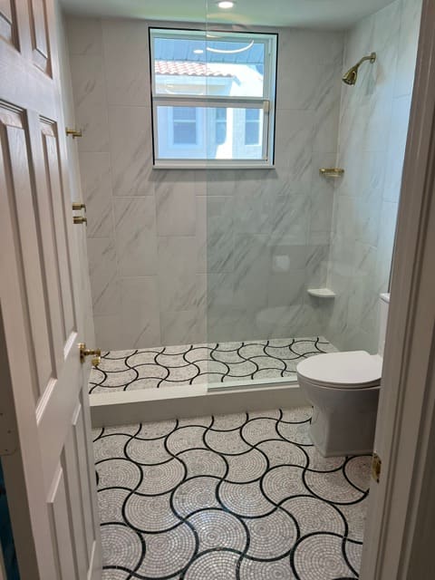Walk-in shower with decorative circular mosaic floor tile and marble walls