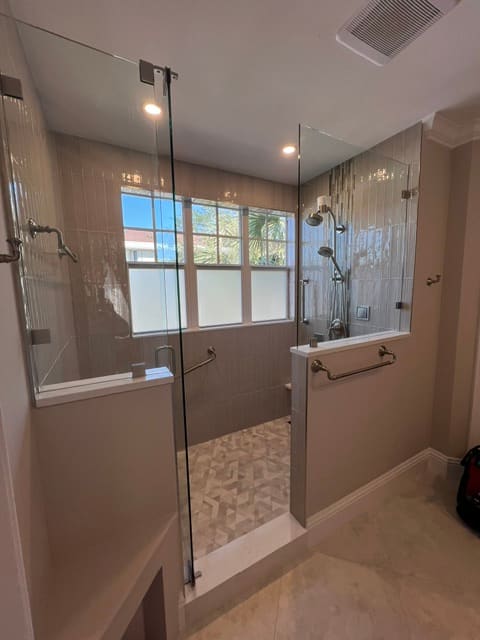 Dual entry walk-in shower with frameless glass and herringbone floor
