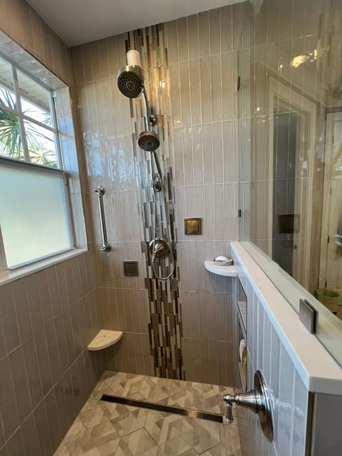 Walk-in shower with vertical mosaic tile feature and dual showerheads