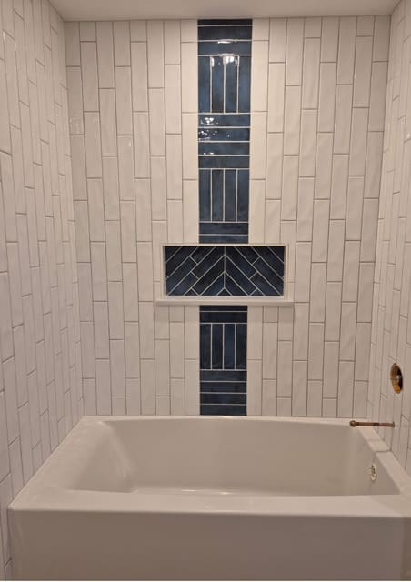 Custom tub surround with vertical white tile and navy mosaic accent