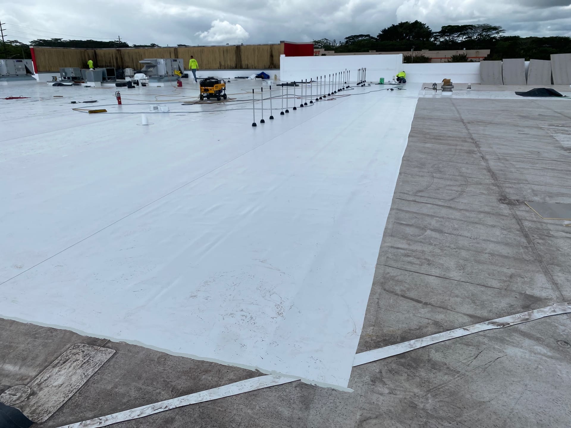 Wide view of commercial TPO membrane being installed over concrete deck