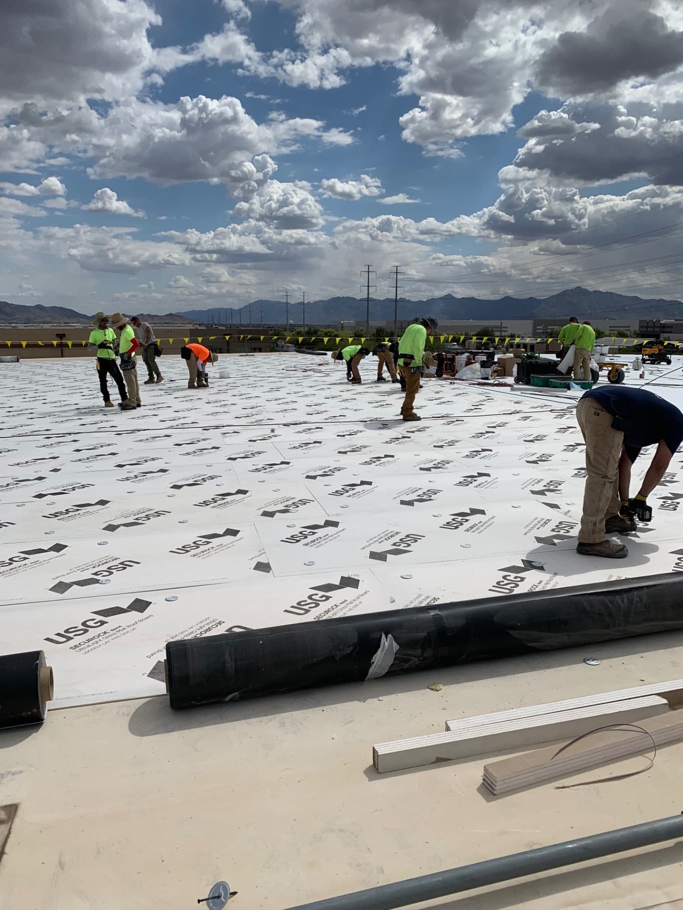 Titan Builder roofing crew installing USG SECUROCK gypsum cover board on large commercial TPO roof