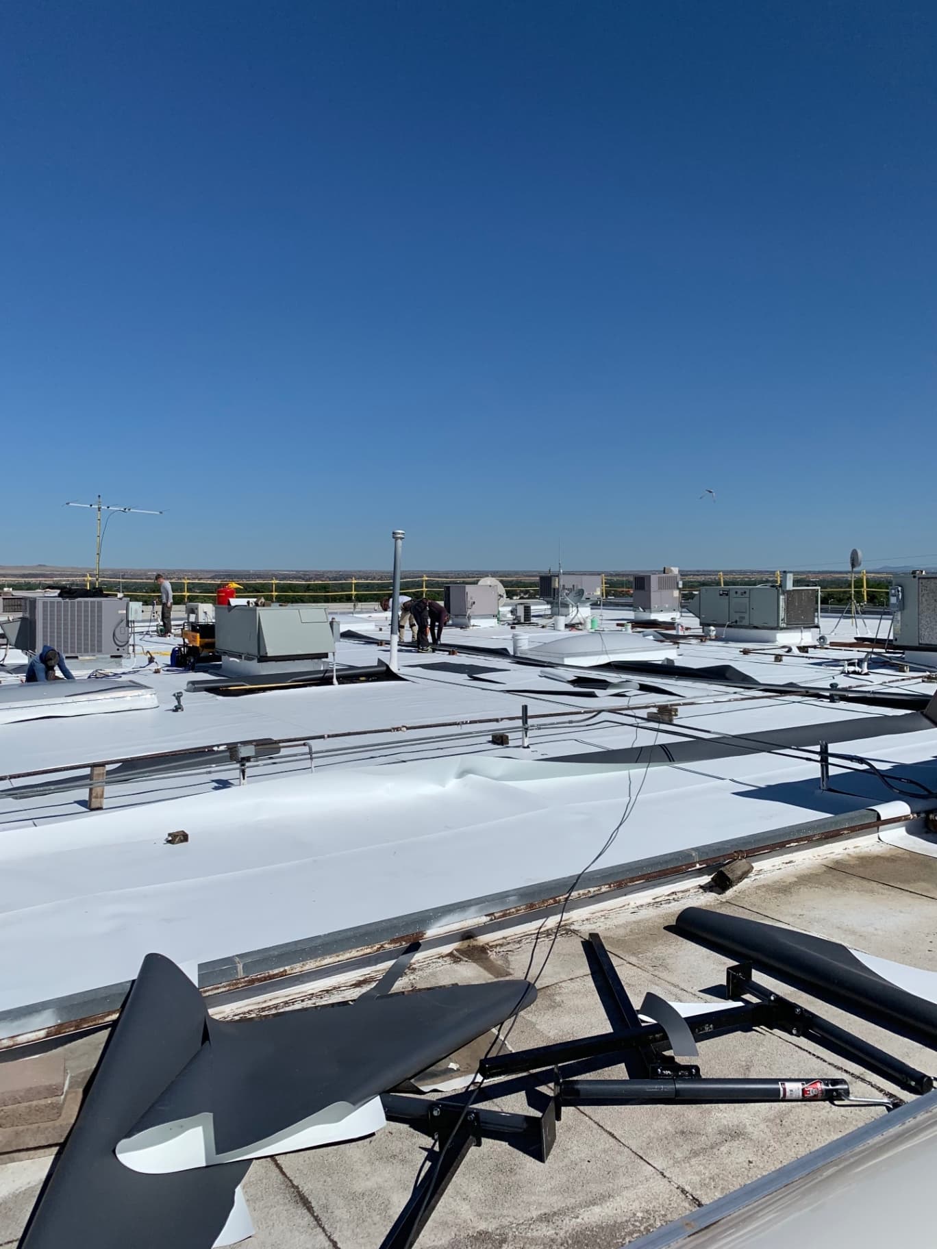 Wide overview of large commercial TPO membrane installation across rooftop with HVAC equipment