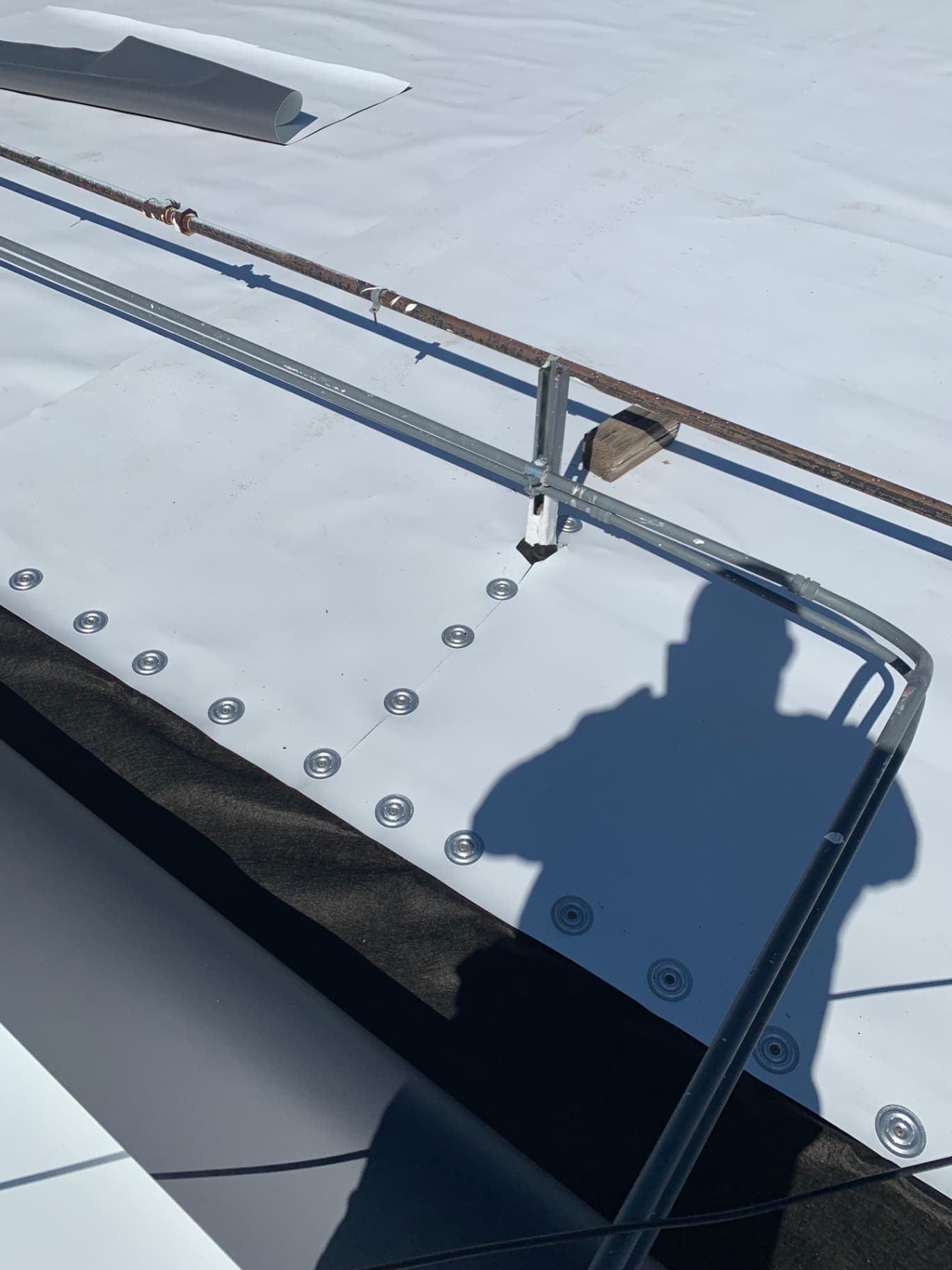 Close-up detail of TPO membrane mechanical fasteners and barbed plates on commercial roof