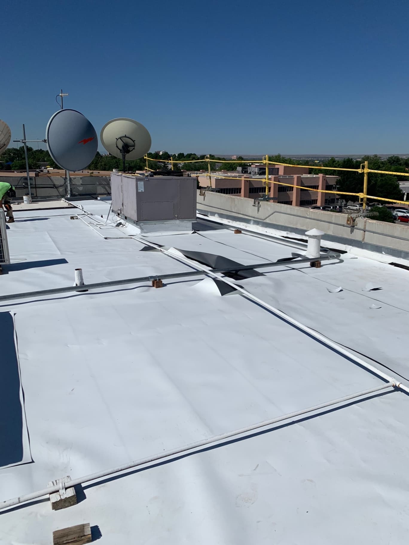 White TPO membrane installed around rooftop satellite dishes and mechanical equipment